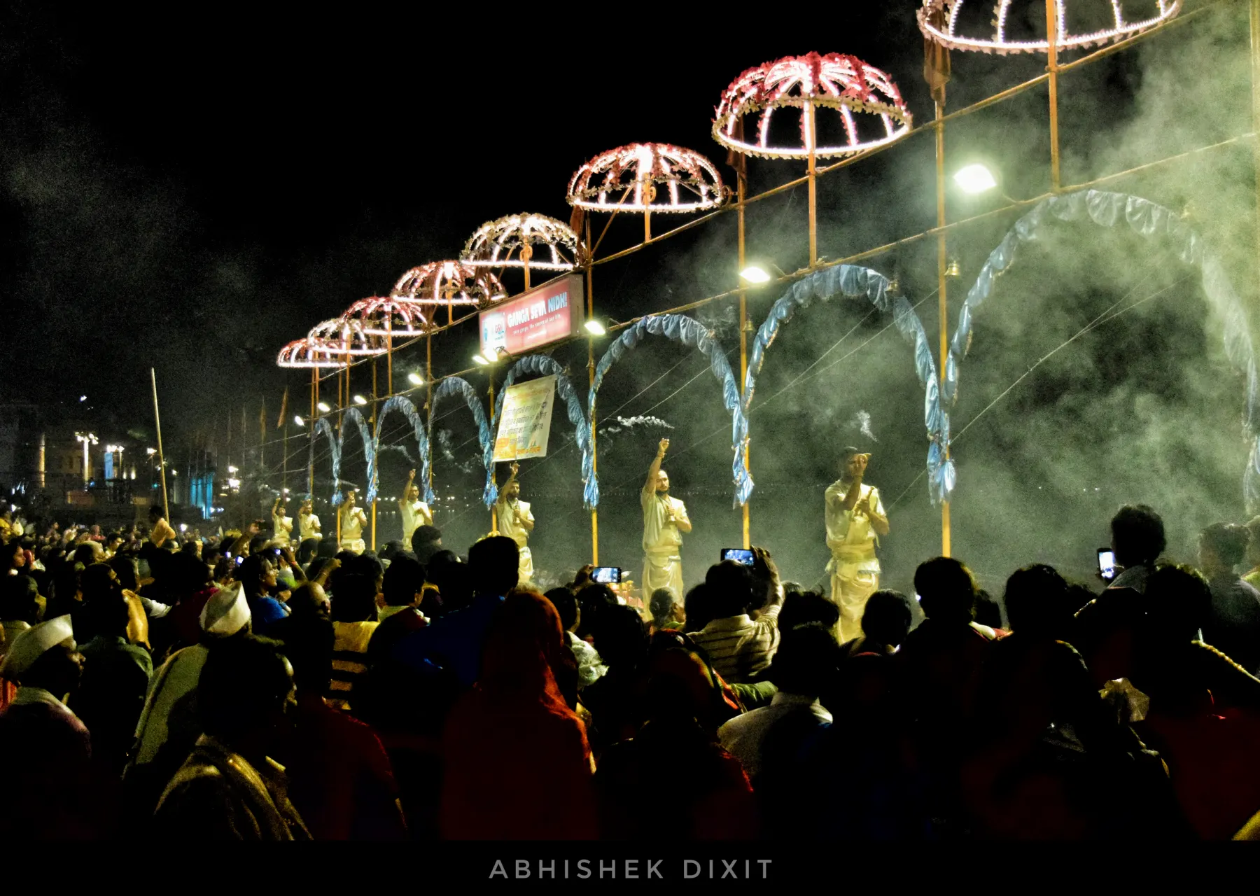 Priests performing the evening Ganga Aarti under lit umbrellas