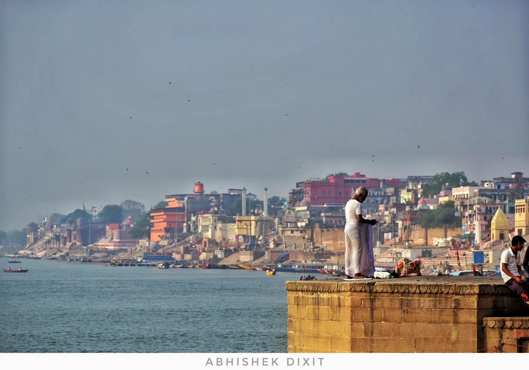 A priest on a platform with the Varanasi ghats stretching behind